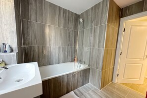 A modern bathroom with a white sink, a bathtub, and a shower.