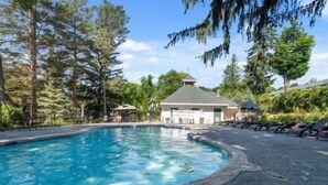 A swimming pool with lounge chairs and a gazebo, surrounded by trees.