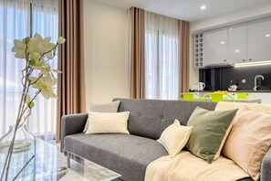 A modern living room with a grey sofa, a glass coffee table, and a vase with white flowers. - Beco Santa Emilia 3J, a Home in Madeira (Funchal)