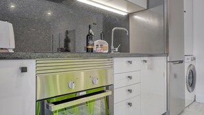 A modern kitchen with stainless steel appliances, a built-in oven, and a washing machine.