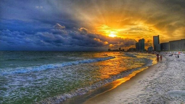 A beach with waves, a sunset, and a city skyline in the background. - Lagoon Front w/Boat Launch & Parking~2BR/1B (Gulf Shores)
