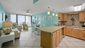 Een ruime woonkamer met een balkon, een keuken met houten kastjes en een eethoek met een tafel en stoelen.