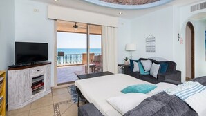 Hotelkamer met balkon, een bed, een sofa, een televisie en een kleintje tafeltje.