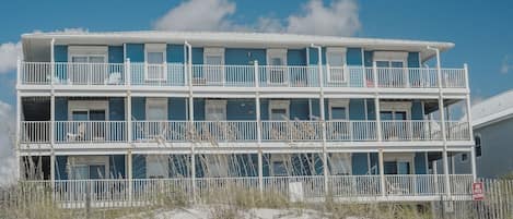A multi-story beachfront hotel with balconies and a 'No Pets Allowed' sign.