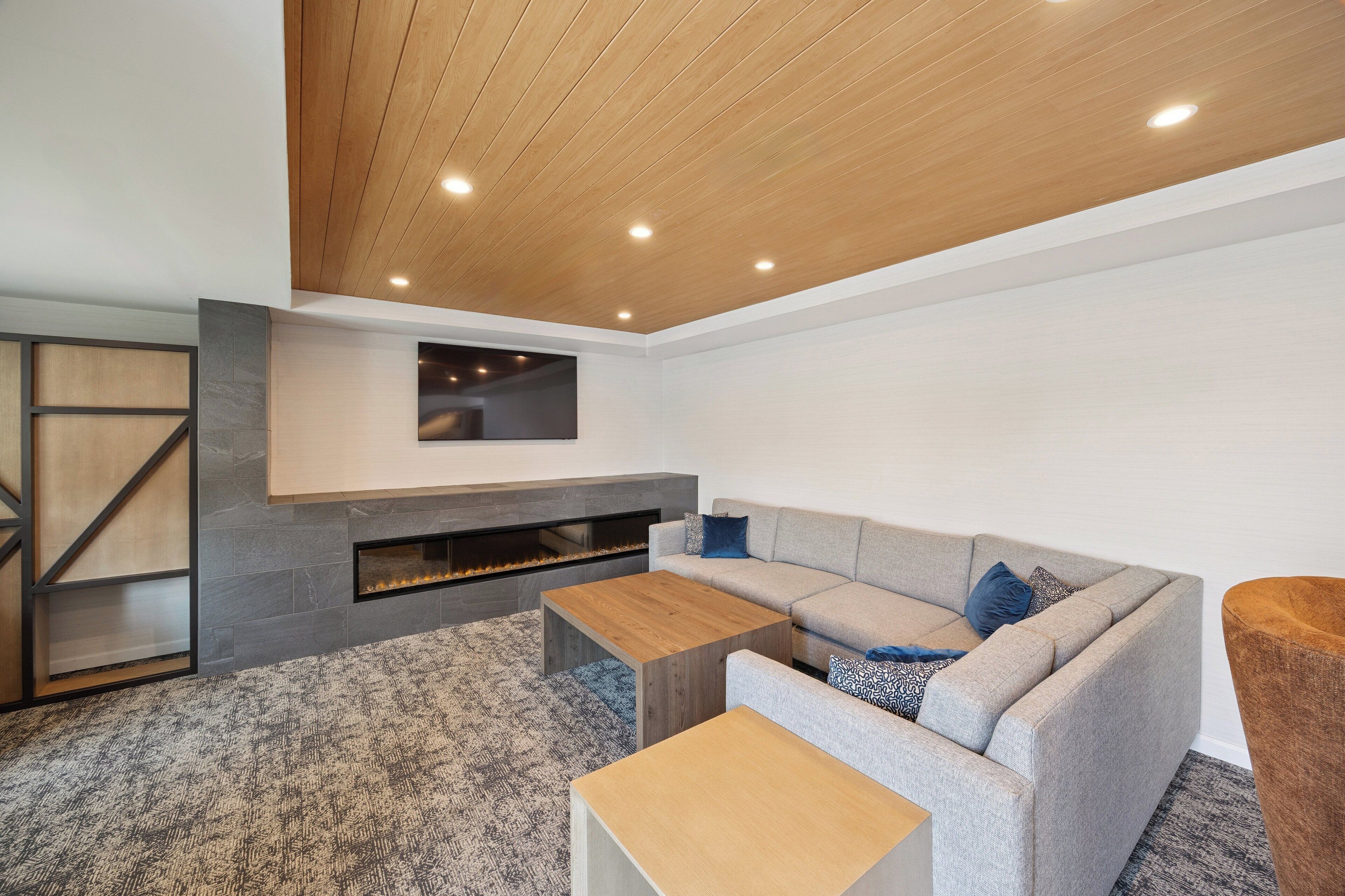 A modern living room with a sectional sofa, a coffee table, a fireplace, and a mounted TV.