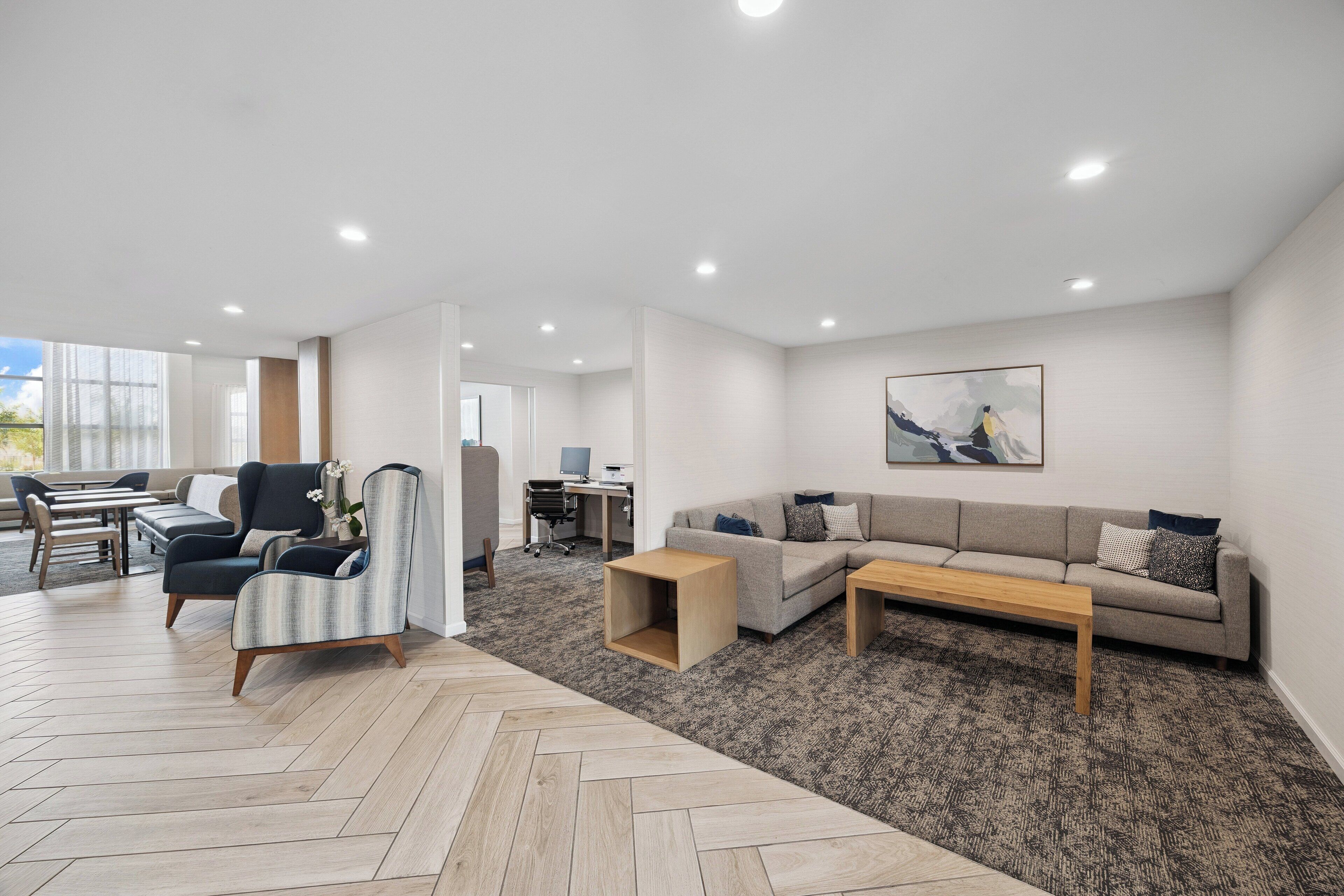A modern living room with a sofa, armchair, coffee table, and a herringbone-patterned floor.