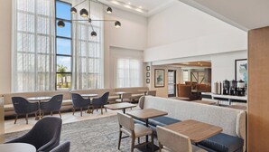 A modern hotel lobby with seating areas, large windows, and a coffee station. - Staybridge Suites Sacramento - Woodland by IHG (Woodland)