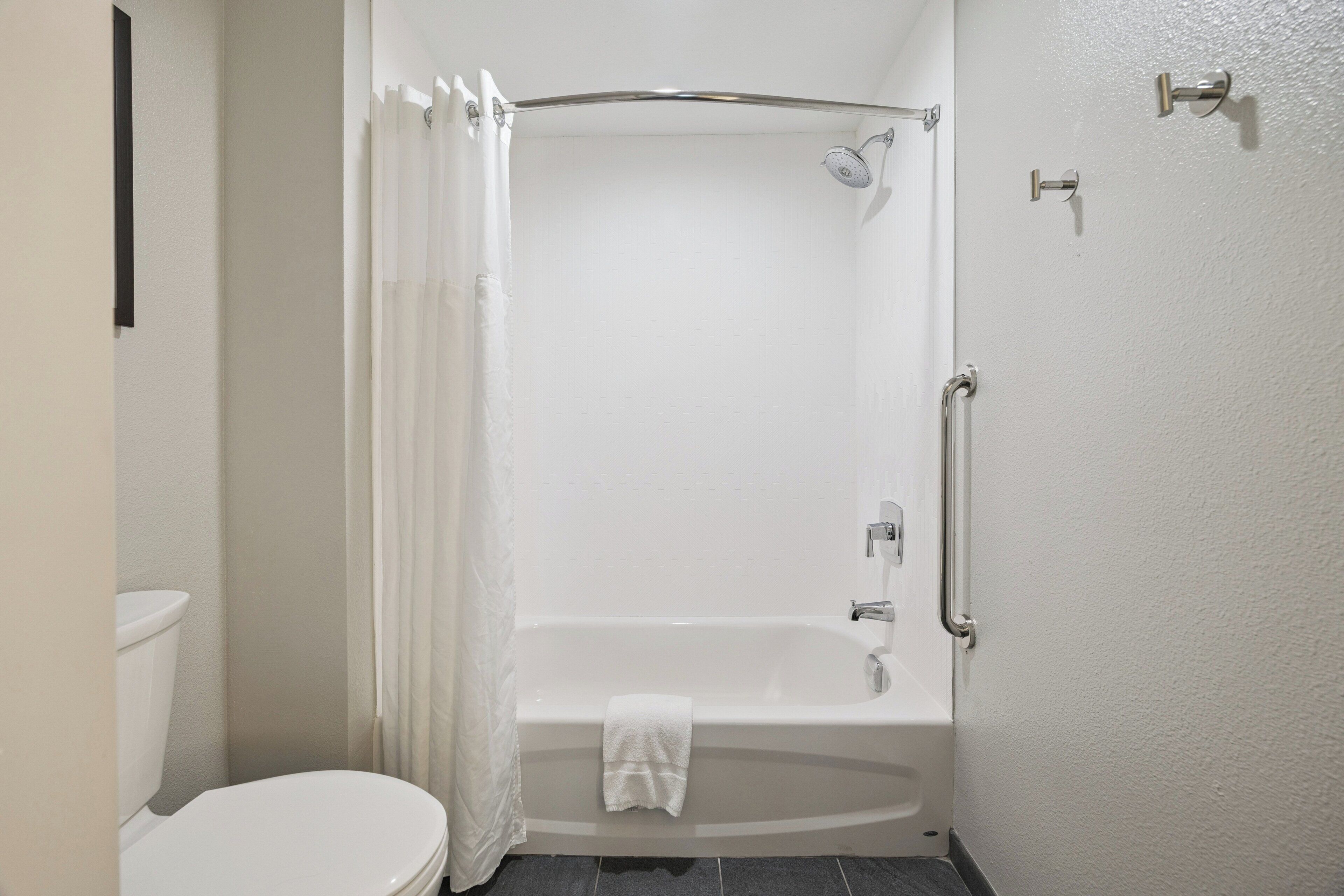A bathroom with a white bathtub, a shower, and a toilet.