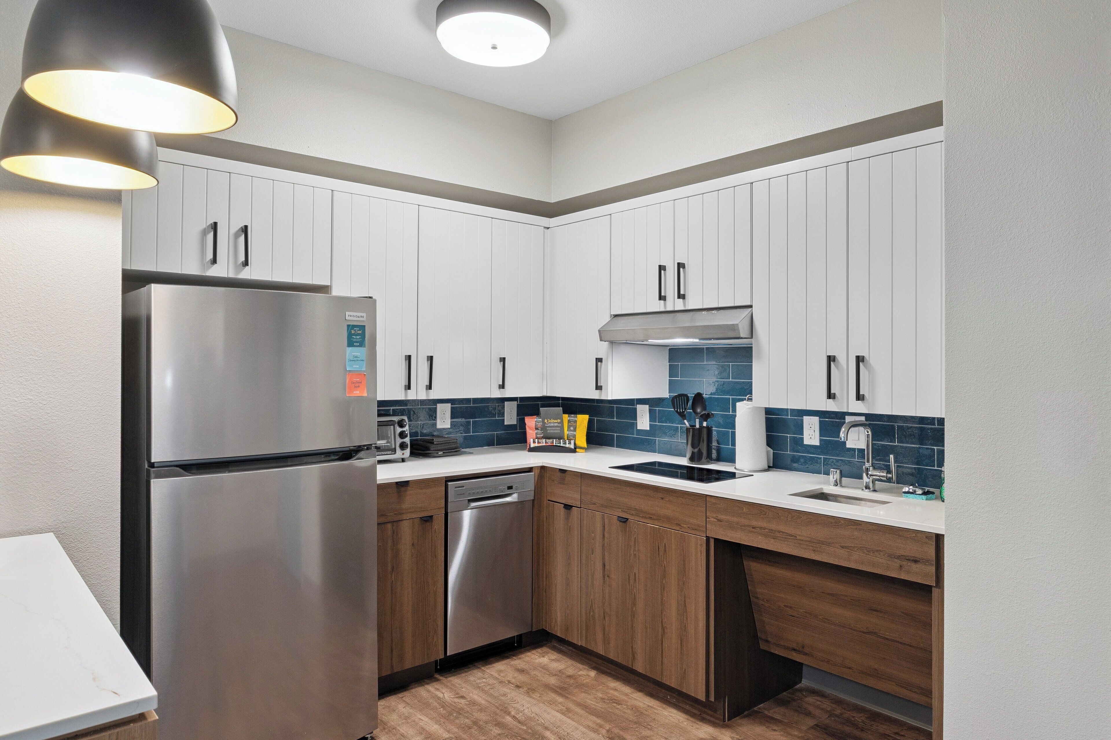 A modern kitchen with white cabinets, stainless steel appliances, and a wooden countertop.