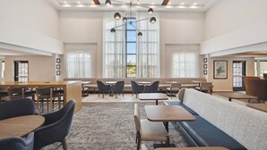 A spacious indoor area with multiple seating arrangements including tables, chairs, and a long bench. - Staybridge Suites Sacramento - Woodland by IHG (Woodland)
