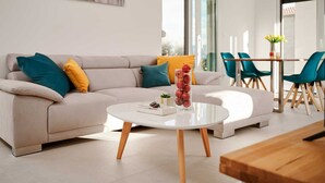 Een moderne woonkamer met een bank, een salontafel en een eethoek met stoelen.