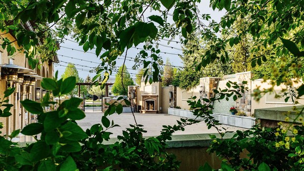 A courtyard with a stone wall, a metal gate, and greenery. - Loaded Logan Loft near USU & EVERYTHING Else - Sleeps 8 in beds (North Logan)