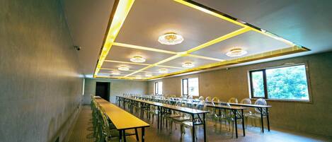 A conference room with long tables and chairs, a modern ceiling design, and large windows.
