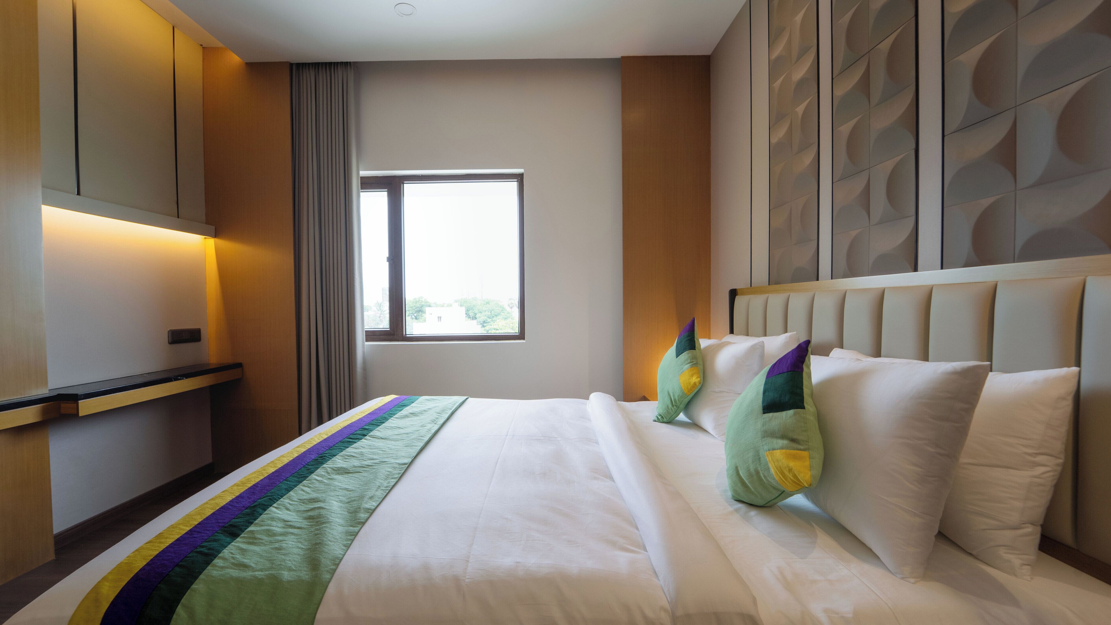 A hotel room with a bed, a window, and a wall with a geometric pattern.