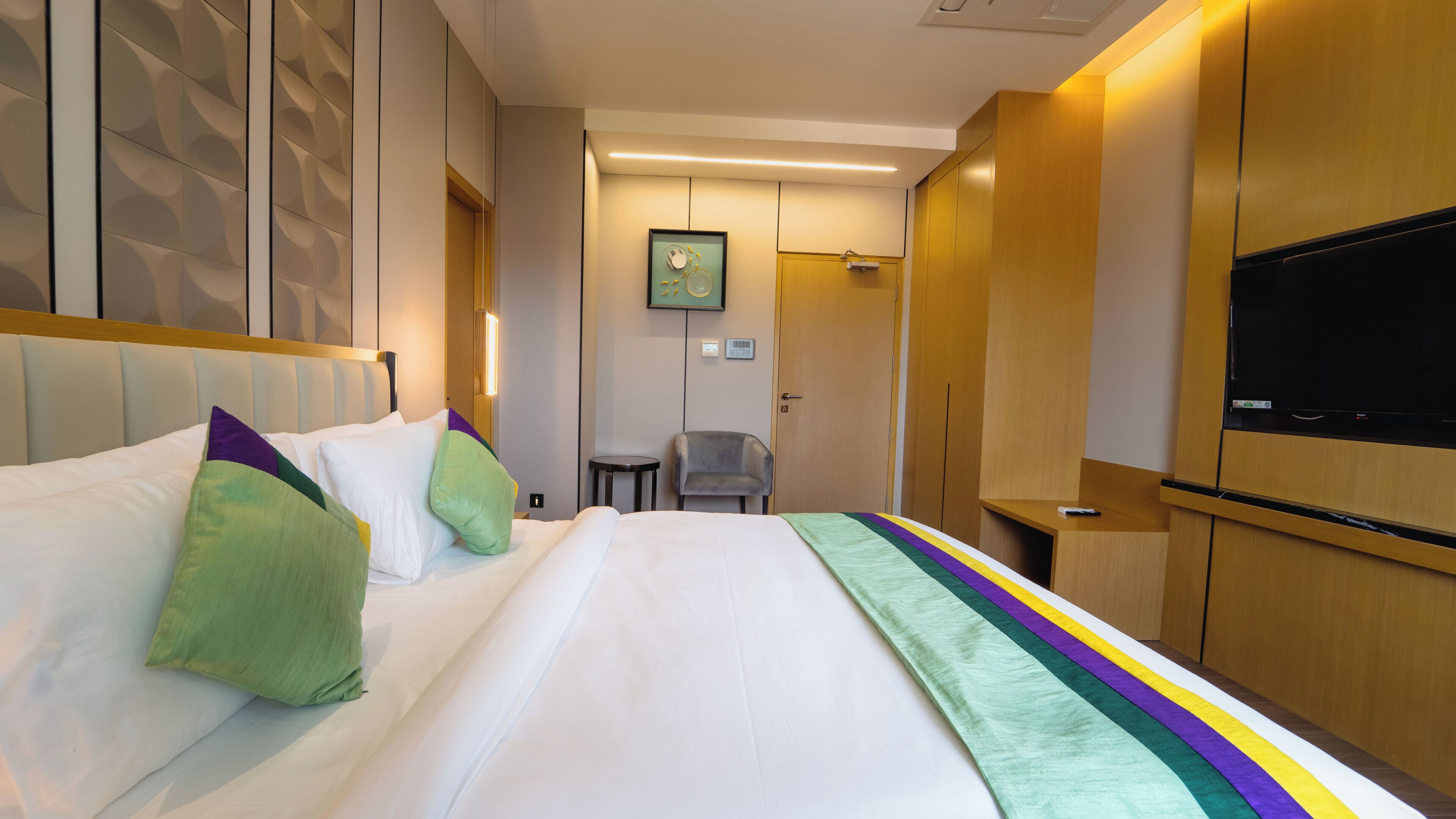 Een hotelkamer met een groot bed, een televisie, een bureau en een stoel.