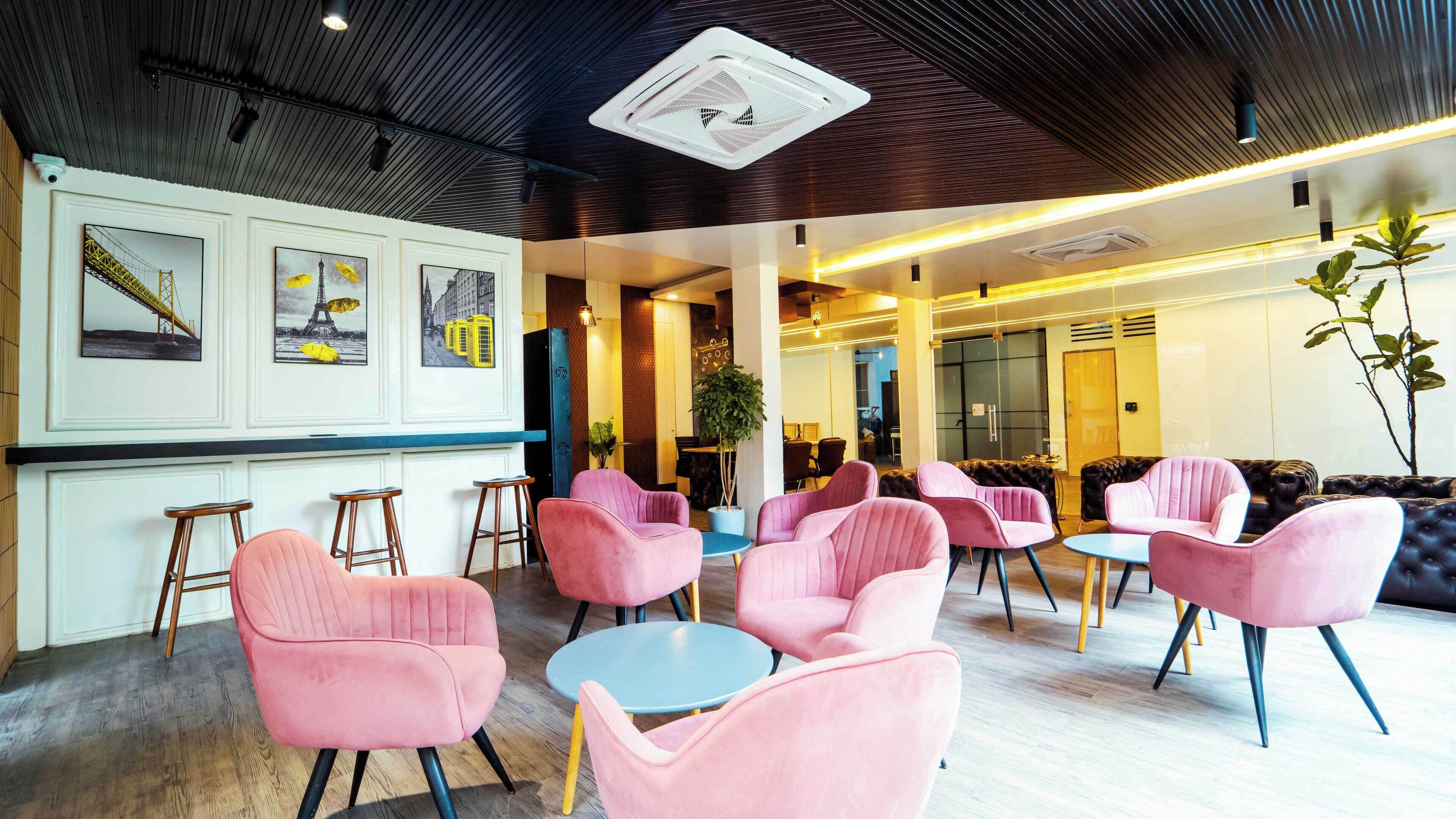 Um interior moderno com cadeiras rosa, área de bar e quadros nas paredes.