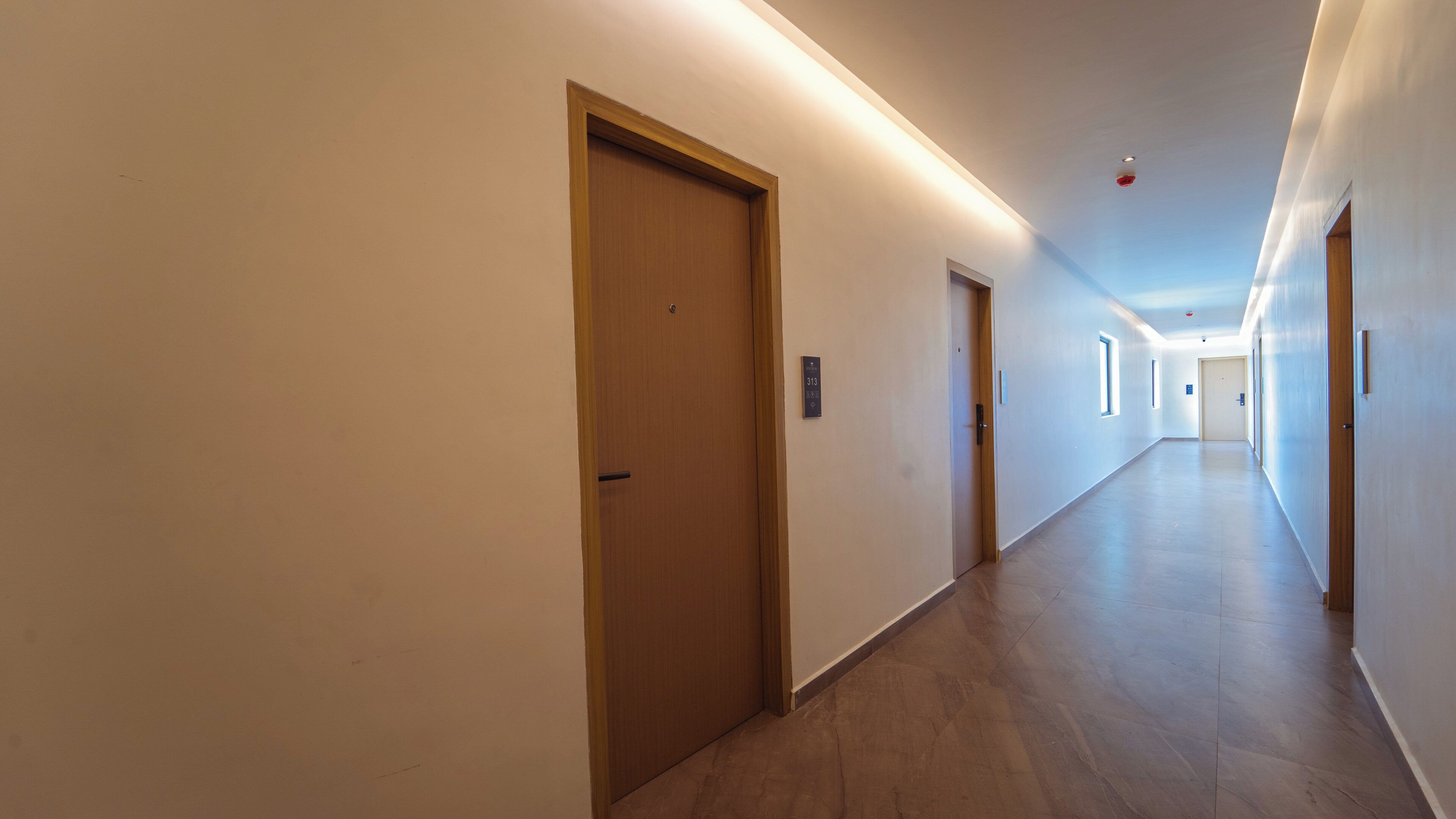 A long, well-lit hallway with wooden doors and a clean, modern design.