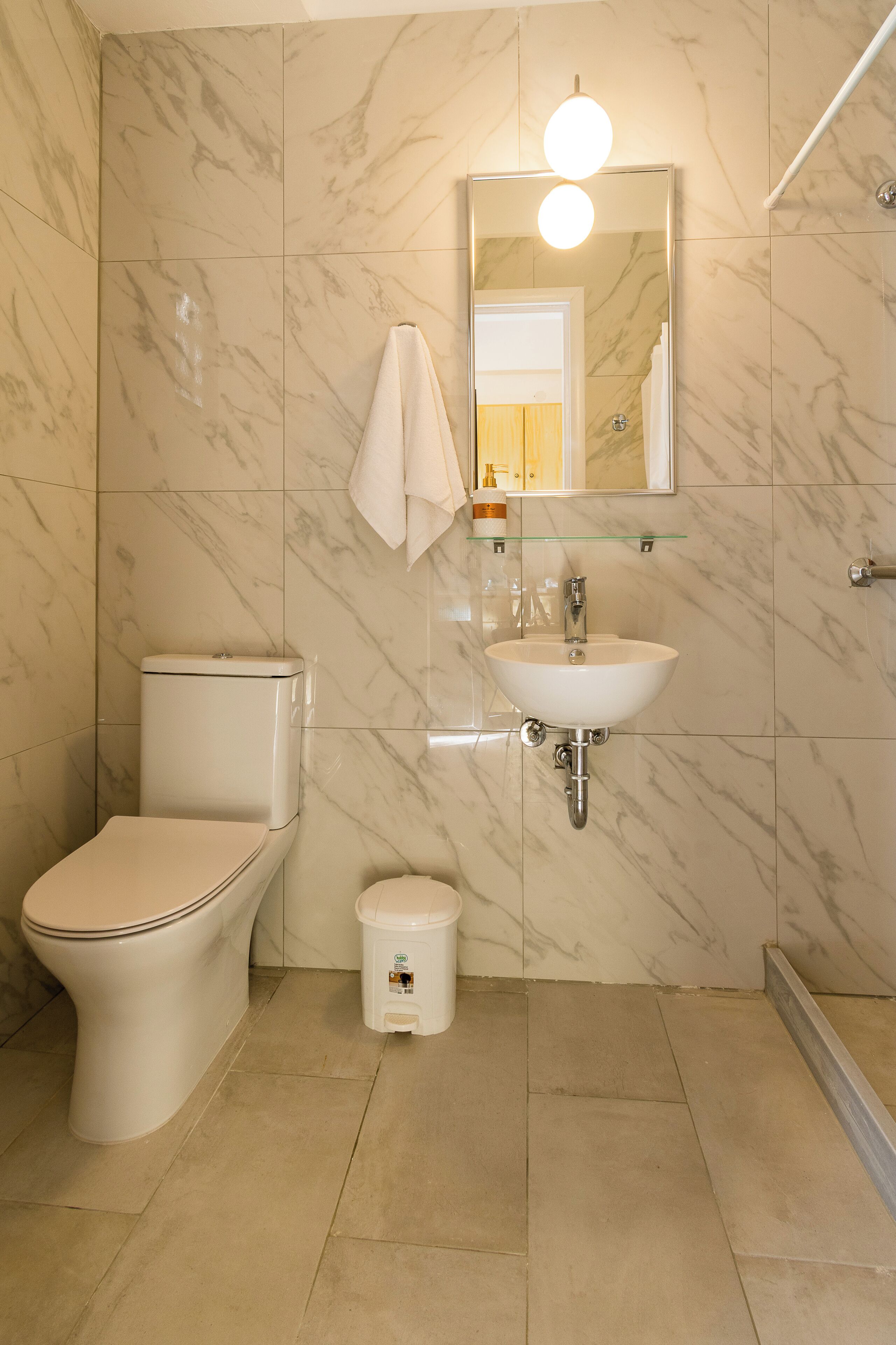 A bathroom with a toilet, sink, and mirror.