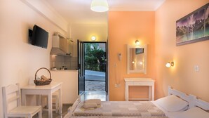 Une chambre d’hôtel avec un lit, une petite table, une chaise, une télévision et une salle de bain équipée d’un miroir et d’un éclairage.