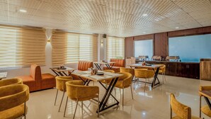 Un espace repas moderne doté d’un haut plafond, de stores en bois et d’un comptoir-bar équipé d’appareils électroménagers.