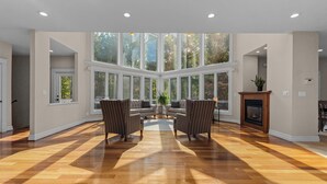 Un salon spacieux doté d’une grande fenêtre, d’une cheminée et d’un espace salon central.