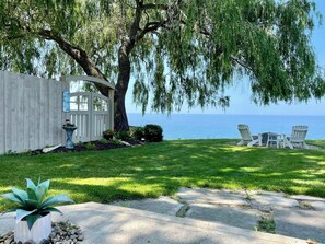 A well-maintained backyard with a patio, seating area, and a view of the sea. - Relax on Lake Erie at our charming 2-bedroom cottage (Willoughby)