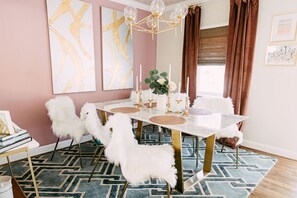 A dining area with a white table, gold legs, white fluffy chairs, a blue patterned rug, and a gold chandelier. - Lucky Number 7 by Pettigrew Adventures (Memphis)