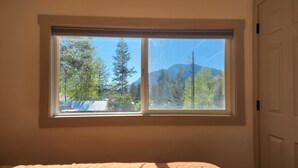 Une pièce dotée d’une grande fenêtre donnant sur une montagne et des arbres.