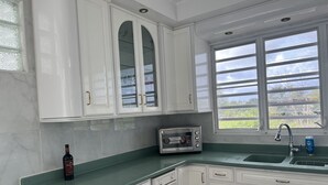 A kitchen with white cabinets, a built-in microwave, a sink, and a window with a view of greenery. - Villa Destiny Family Friendly Destination with private pool & jacuzzi &more. (Cacao)