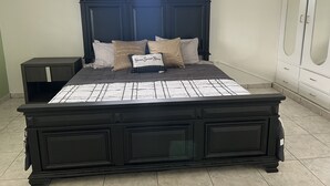 A bedroom with a dark wood bed, beige and brown pillows, a small bedside table, and a wardrobe with mirrored doors. - Villa Destiny Family Friendly Destination with private pool & jacuzzi &more. (Cacao)