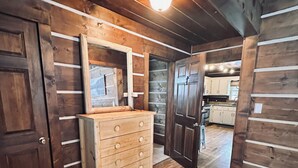 Interior de madera con un aparador, un espejo y una puerta que da a la cocina.