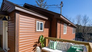A wooden deck with a sofa and a table, a small window, and a door. - Chic Catskills Cabin w/ Fireplace, Firepit, 30min to Ski Big Bear Resort. (Cochecton)