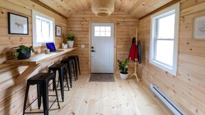 A wooden interior with a door, a bench, a laptop, and a potted plant. - Chic Catskills Cabin w/ Fireplace, Firepit, 30min to Ski Big Bear Resort. (Cochecton)