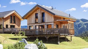 Eine Holzhütte mit Balkon, gelegen an einem Hang mit Bergblick.
