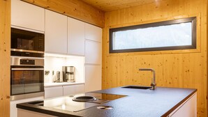 Eine moderne Küche mit Edelstahlgeräten, einer schwarzen Arbeitsplatte und einem Fenster über der Spüle.