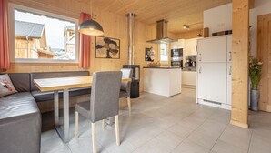 A modern kitchen with a central island, wooden walls, and a large window overlooking a wooden deck.