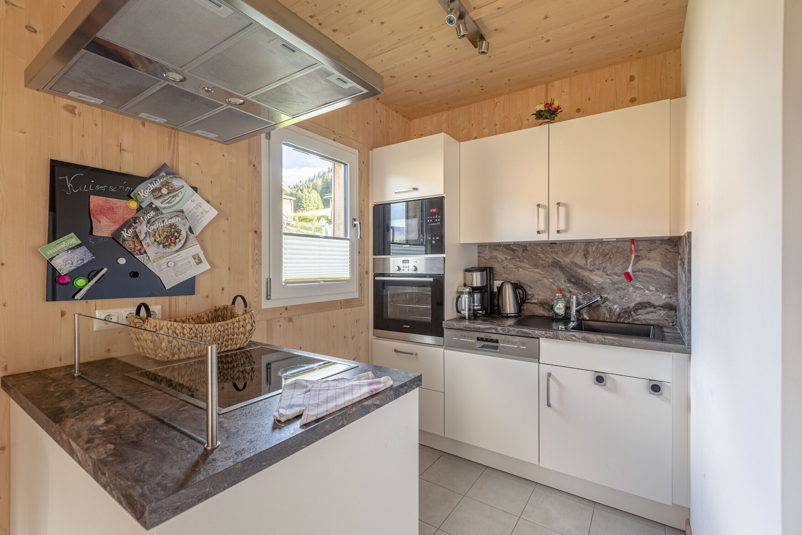 Una cocina moderna con armarios blancos, horno empotrado y extractor de acero inoxidable.