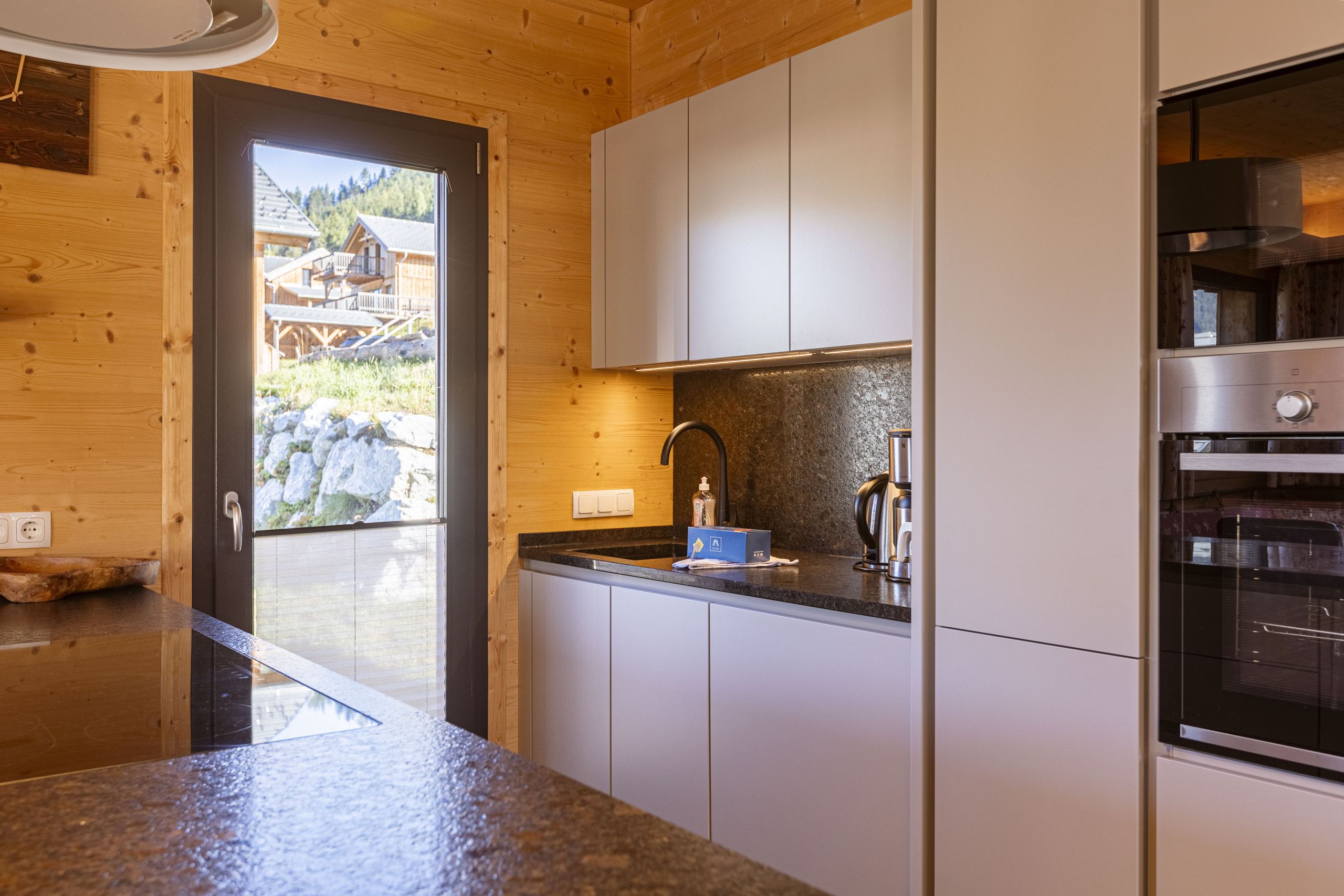 Eine moderne Küche mit Holzwänden, weißen Schränken und einem großen Backofen.