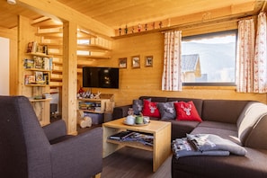 A cozy wooden interior with a sofa, coffee table, and bookshelves.