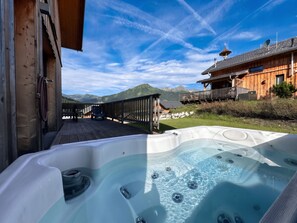 A hot tub with a wooden deck and a view of mountains.