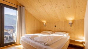 Una stanza in legno con un letto, una finestra e due luci fissate al muro.