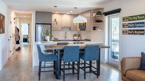 A modern kitchen with a central island, bar stools, and pendant lighting. - The Big Deck by Revelstoke Vacations (Revelstoke)