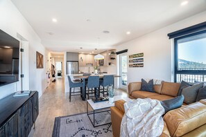 Een moderne woonkamer met een bank, salontafel en uitzicht op een keuken en eetgedeelte.