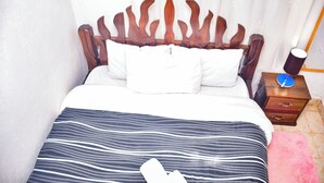 Un lit avec une couvre-lit à rayures, une tête de lit en bois et des oreillers blancs.