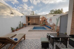 Eine Terrasse mit Pool, Sitzgelegenheiten und Wandgemälde.