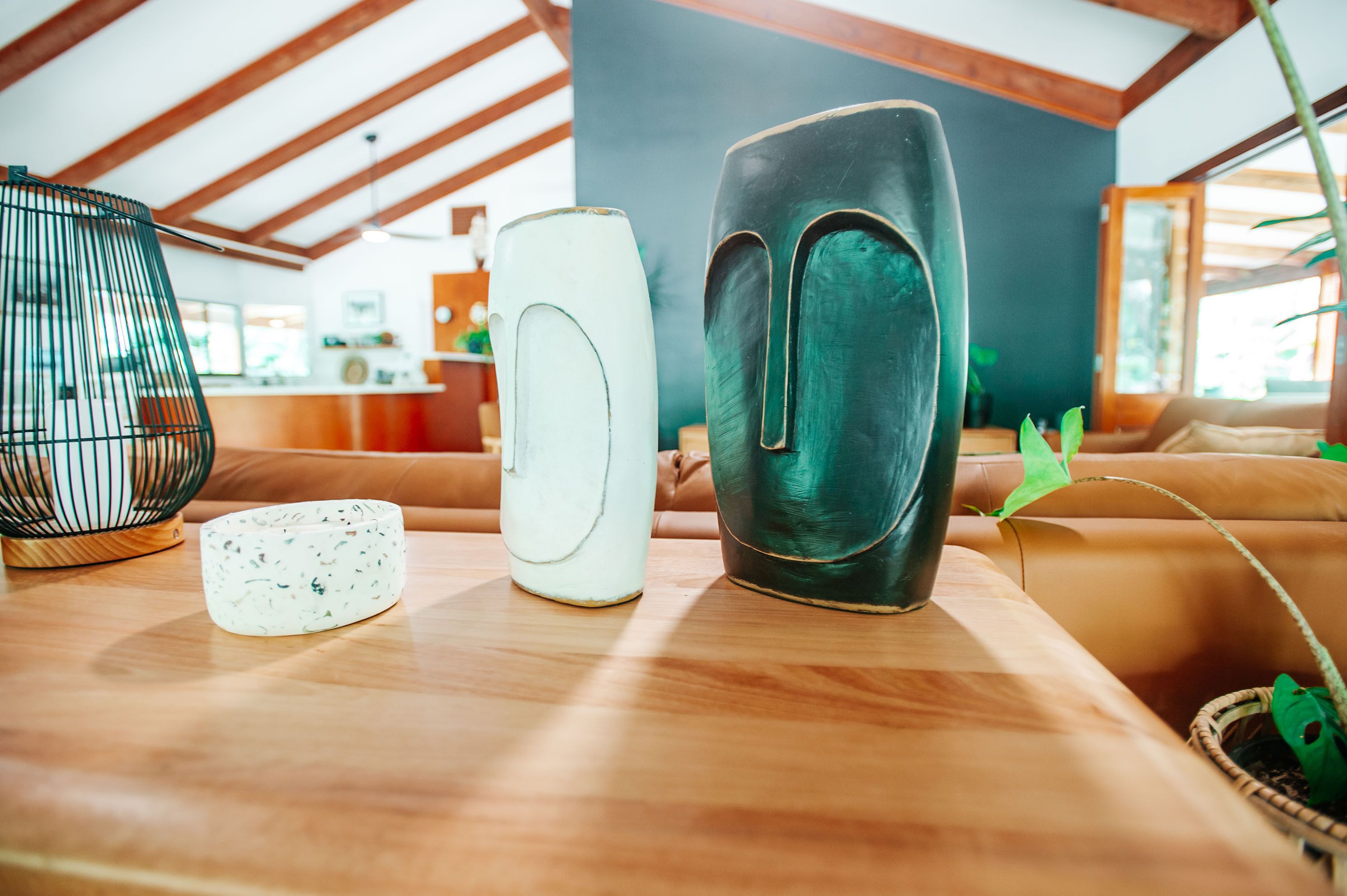 Una mesa de madera con tres jarrones y un adorno.