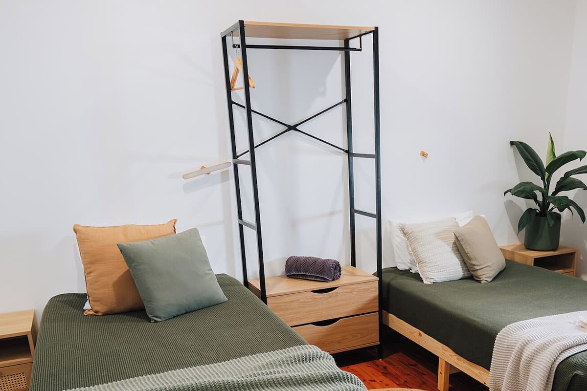A bedroom with a wooden bed, a bench, a small table, and a hanging chair.