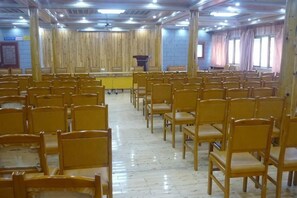 Une salle de conférence avec des rangées de chaises et un pupitre à l’avant.