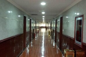Un long couloir étroit, doté d’un plancher poli et de portes de part et d’autre.