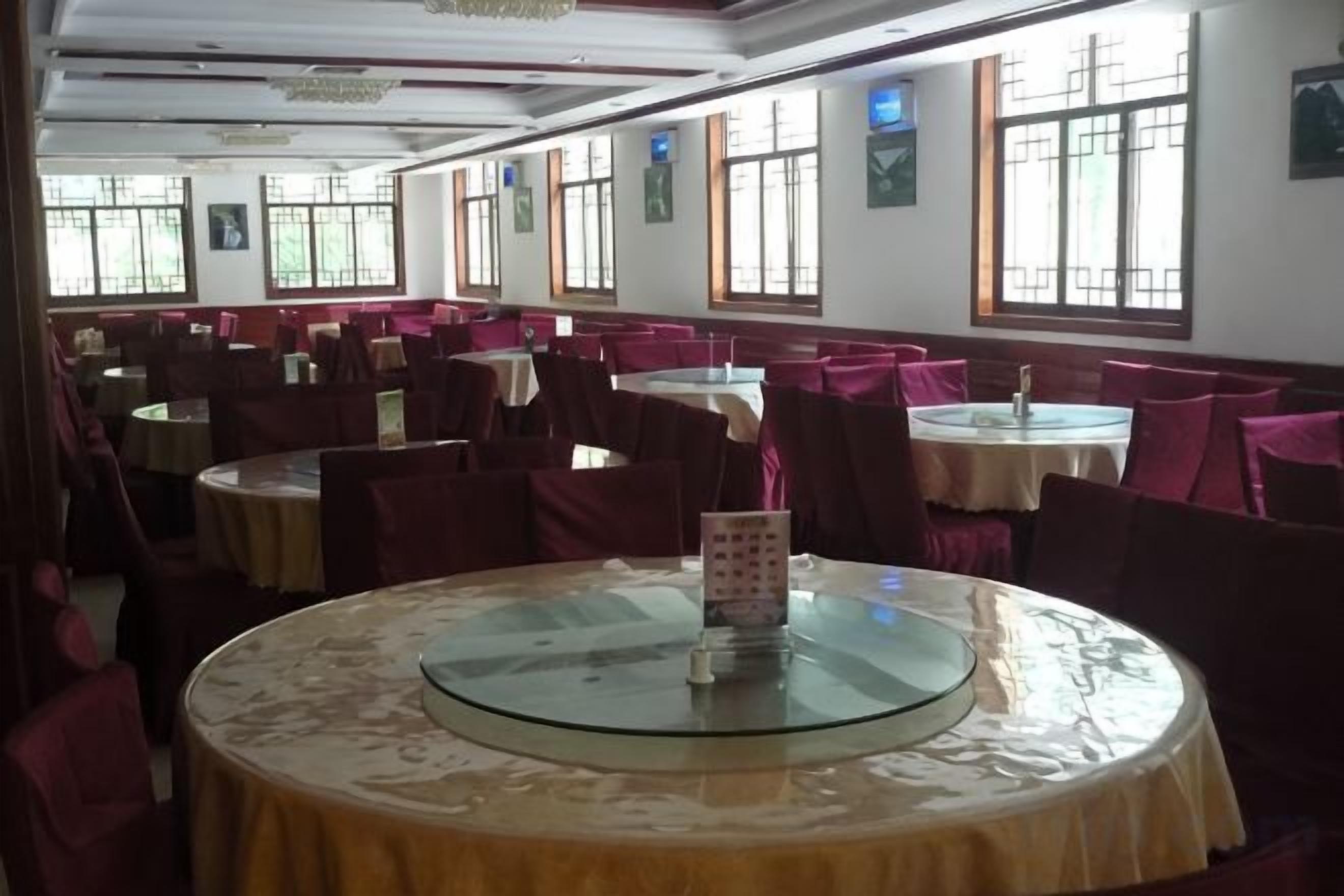 Un espace repas avec des tables rondes, des chaises et une table à plateau de verre recouverte d’une nappe.